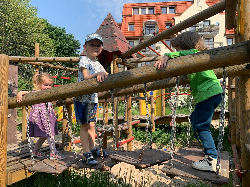 Dzieci przechodzące przez most zwodzony na placu zabaw.